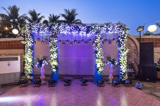 Outdoor stage with floral arch beautiful decorations, lighting, and seating under a twinkling sky.