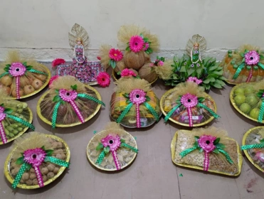 Assorted colorful fruit baskets adorned with flowers and ribbons on a beige floor against a wall.