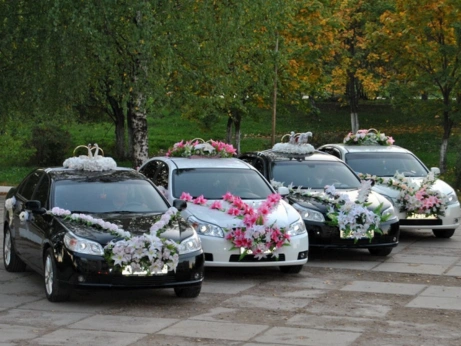 Four elegantly decorated cars adorned with flowers showcase premium wedding transportation services
