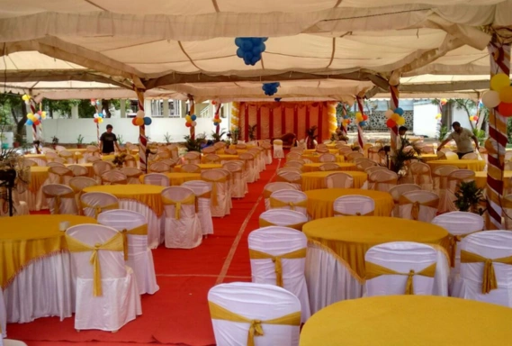 A banquet hall adorned with neatly set tables & chairs, creating an inviting atmosphere for gatherings.